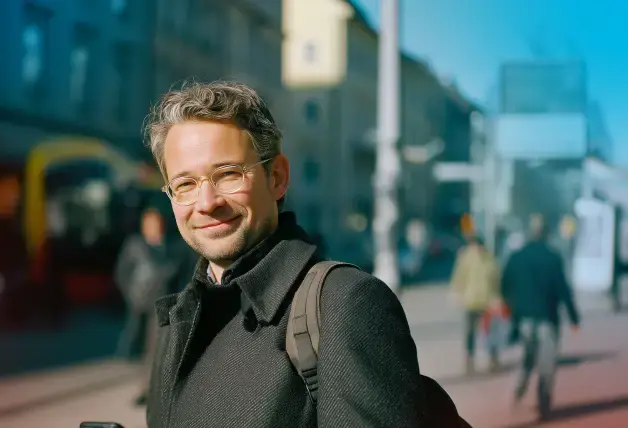 ein Mann in der Stadt mit Smartphone in der Hand schaut zufrieden in die Kamera