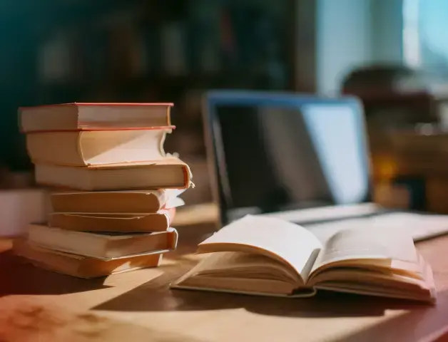 ein Stapel Bücher liegt vor einem Laptop