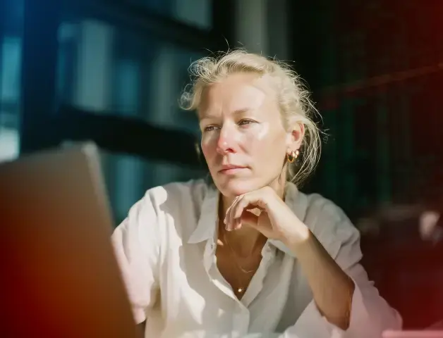 eine Frau mittleren Alters schaut nachdenklich in einen Laptop
