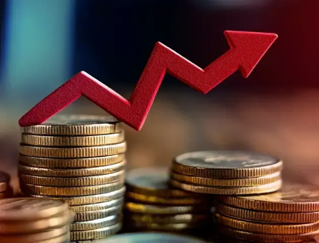 mehrere Stapel Geldmünzen mit einem roten gezackten Pfeil nach oben